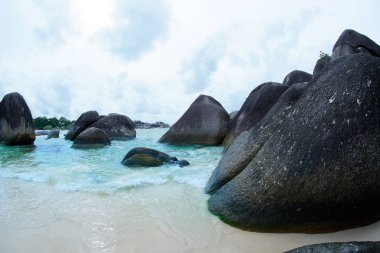 Natural black rock formation on the seashore at the beach in Belitung Island. clipart