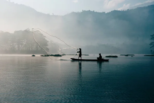 Fisherman casting out his fishing net in the river.