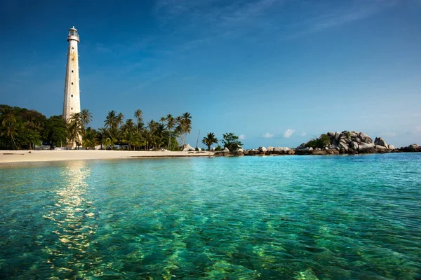 Phare blanc debout sur une île à Belitung pendant la journée entouré d'eau de mer bleu-vert clair . — Photo