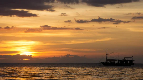 Boat silhouette crossing the ocean towards an orange sunset sky. — Stock Photo, Image