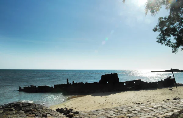 Silhouette di vecchio relitto abbandonato incagliato seduto sulla riva della spiaggia . — Foto Stock
