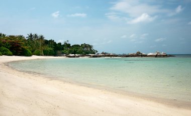 Stretched out white sand beach with natural rock formation at the coastline on the horizon in Belitung Island. clipart