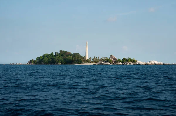 Phare blanc debout sur une île avec formation rocheuse naturelle et végétation verte dans l'île de Belitung, Indonésie . — Photo