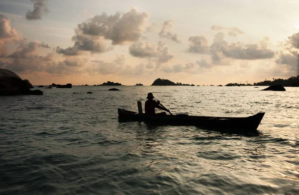 Silhouette of one man rowing a small boat with his paddle on the ocean in Belitung Island, Indonesia. — Stock Photo, Image