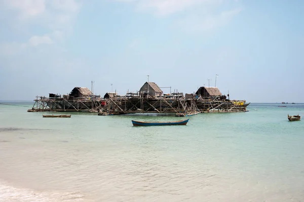 Île de pêche artificielle avec filets de pêche pour pêcher avec et petites maisons flottant près de la côte bleue de l'océan à côté de la plage de sable blanc . — Photo