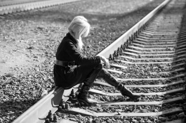 Yalnız sarışın raylar üzerinde oturan