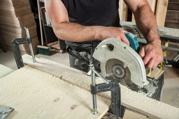 man saws a wide wooden