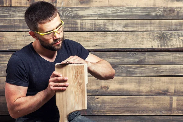 Hombre sierra una tabla de madera —  Fotos de Stock