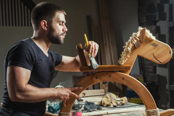 Мужчина рисует деревянную игрушку — стоковое фото