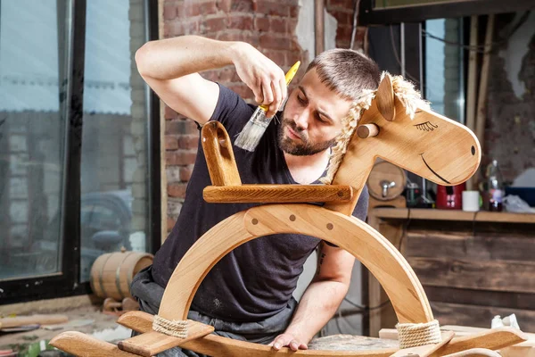 Carpenter maluje dětské dřevěné hračky — Stock fotografie