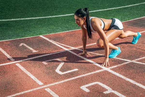 Donna sta in piedi in una partenza bassa per la corsa — Foto Stock