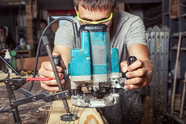 Hombre es igual a una tabla de madera con una fresadora — Foto de Stock