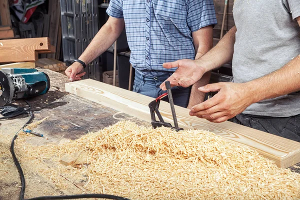 Dos hombres discuten cómo procesar una tabla de madera — Foto de Stock