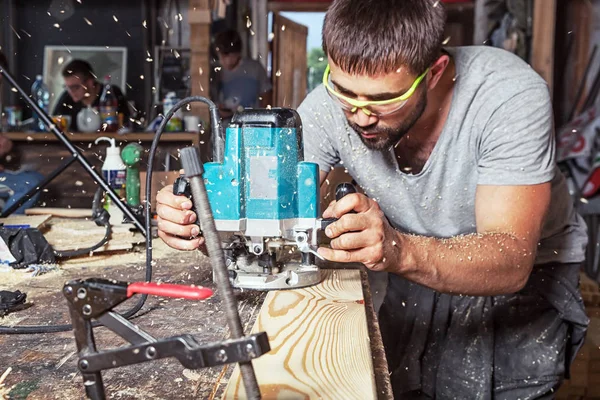 Carpinteiro detém uma máquina de moagem verde — Fotografia de Stock