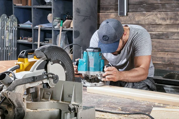 Bauarbeiter hantiert mit Fräsmaschine an einer Holzplanke — Stockfoto