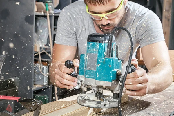 Bauarbeiter hantiert mit Fräsmaschine an einer Holzplanke — Stockfoto