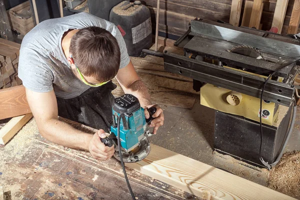 Bauarbeiter hantiert mit Fräsmaschine an einer Holzplanke — Stockfoto