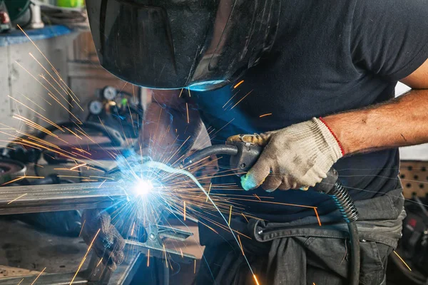 Homem solda um metal com uma máquina de solda — Fotografia de Stock