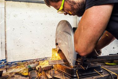 adam kaynakçı bir metal bir daire testere ile keser 