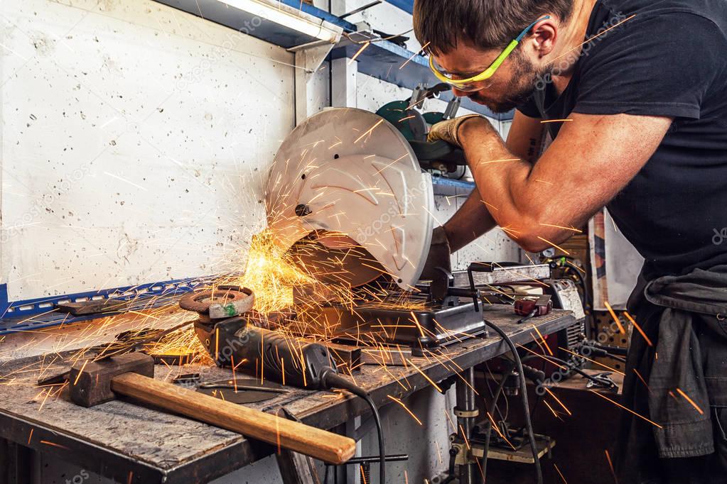 man welder cuts a metal with a circular saw 