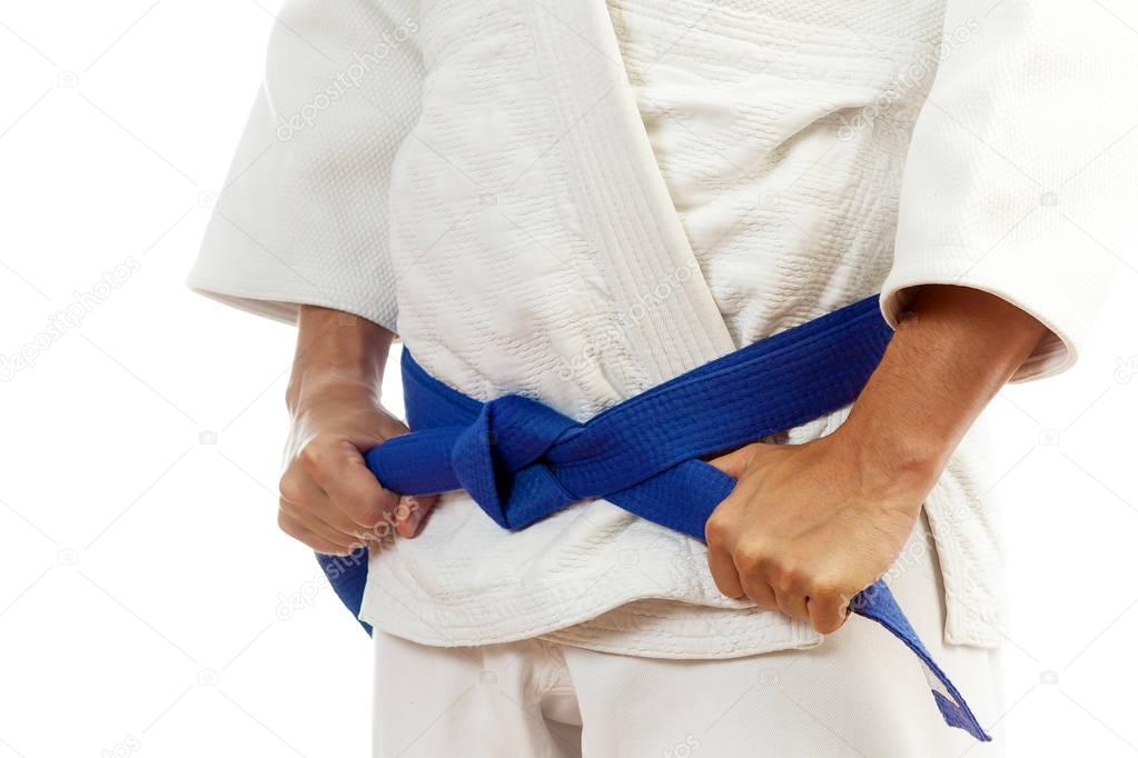 Close-up of a man  in a white kimono for judo, ties up a blue be