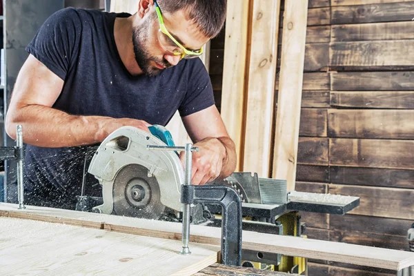 Hombre aserrando madera con una sierra circular moderna — Foto de Stock