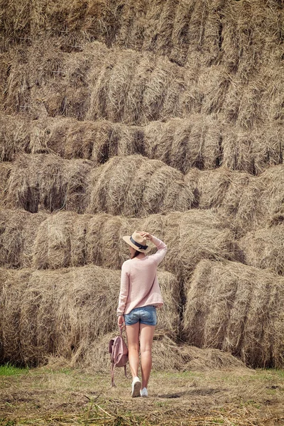 Žena představuje proti stohy — Stock fotografie