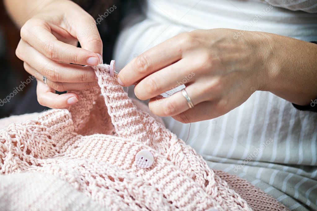 close up woman sews a button