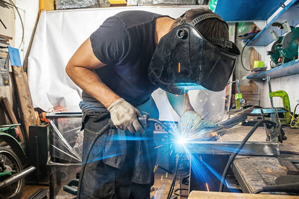 man welds with a welding machine