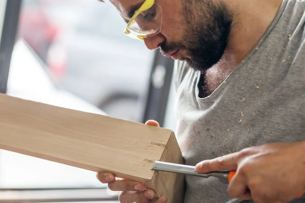 Uomo che tratta un prodotto in legno con uno scalpello — Foto Stock