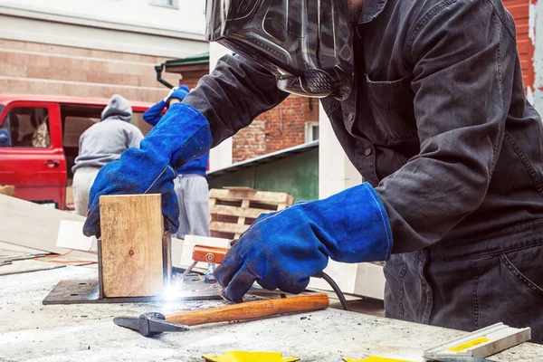 Soldador está soldando uma construção metálica — Fotografia de Stock