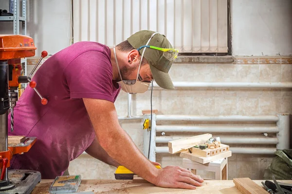 一位年轻强壮的人造木匠用木棍在车间里做家具 量身定做和裁剪 背景是许多工具和工作条件 — 图库照片