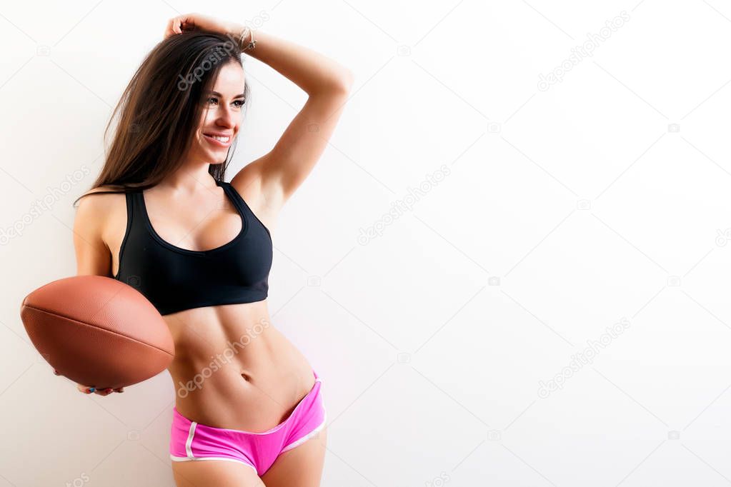 Dark-haired young woman fitness model smile, holds a  rugby ball