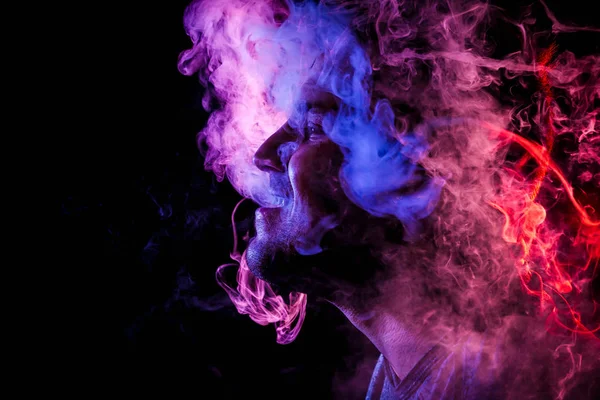 人是党员从电子香烟喷出的蒸汽 红色和粉红色的彩色烟雾云的黑色孤立 以年轻劫匪为例对吸烟的危害 — 图库照片
