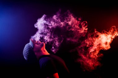Bir mod tutarak Vaping adam. Buhar bulutu. Siyah arka plan. Vaping elektronik sigara duman bir sürü ile. Vape kavramı