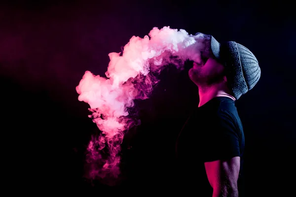 Muž Šedém Klobouku Černé Tričko Vydechuje Vícebarevné Kouř Elektronické Cigarety — Stock fotografie