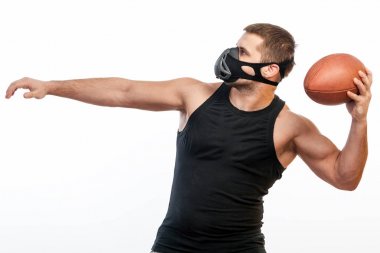 Genç bir erkek atlet siyah eğitim maskeli bir spor gömlek beyaz izole arka planda bir ragbi topu tarafından sallanır