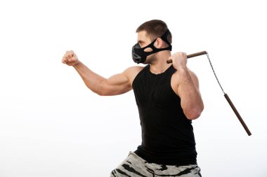 Atletik delikanlı bir spor gömlek, eğitim siyah maske bir nunchaks bir beyaz izole arka plan üzerinde tutar