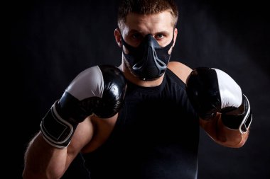 Spor gömlek, eğitim maskesi ve boks eldiven yalıtılmış siyah arka plan üzerinde giyen genç atletik adam portresi