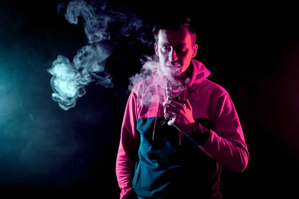 Hombre Fuma Cigarrillo Electrónico Sobre Fondo Humo Rojo Azul — Foto de Stock