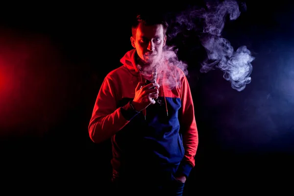Hombre Fuma Cigarrillo Electrónico Sobre Fondo Humo Rojo Azul — Foto de Stock