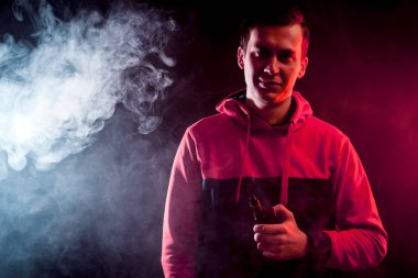 Adam elektronik sigara, vape kırmızı ve beyaz duman bir arka plan üzerinde tutar