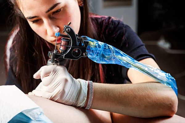 Tattooist making by professional artist is tattooing body woman using machine in a creative design work studio