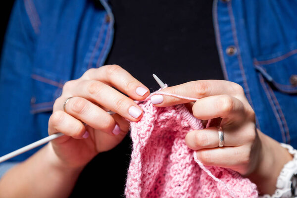 Крупный план женщины в черной футболке и джинсовой рубашке, вязанной натуральными шерстяными нитями розового свитера
