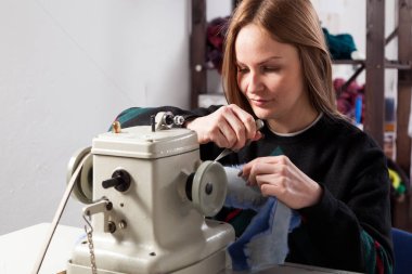 Genç kadın Furrier dikiş mavi kürk manto dikiş makinesi atölye üzerinde