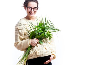 Esmer kadın gülümseyerek ve güzel süsen buket beyaz izole arka plan üzerinde tutarak gebeliğin son gününde sütlü renk yün kazak