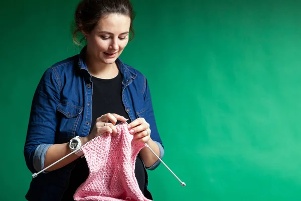 穿着牛仔衬衫的年轻女子针织毛衣从自然羊毛线粉红色的绿色隔离背景 — 图库照片