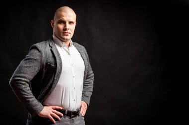 Beyaz bir gömlek bir kel adam işadamı, gri takım elbise siyah bir izole arka plan onun omuzlarında düzleştirme kendine güvenen bir poz duruyor