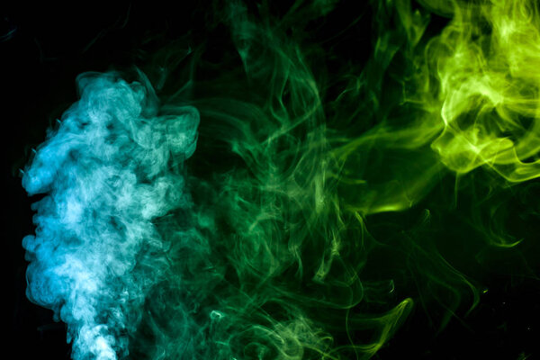 Colorful green and blue smoke clouds on dark background
