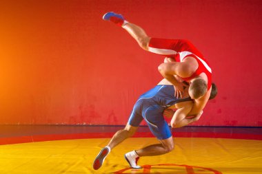 Wrestlng ve halı spor salonunda, sied görünümü güreş bir sarı bir kalça yapma iki genç erkek güreşçiler mavi ve Kırmızı tayt güreş vardır